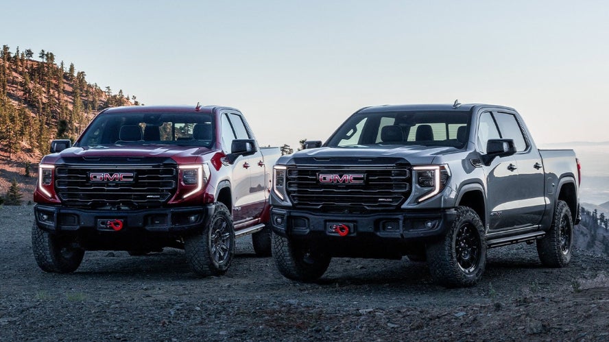 Two 2027 GMC Sierra 1500 pickup trucks parked in the mountains